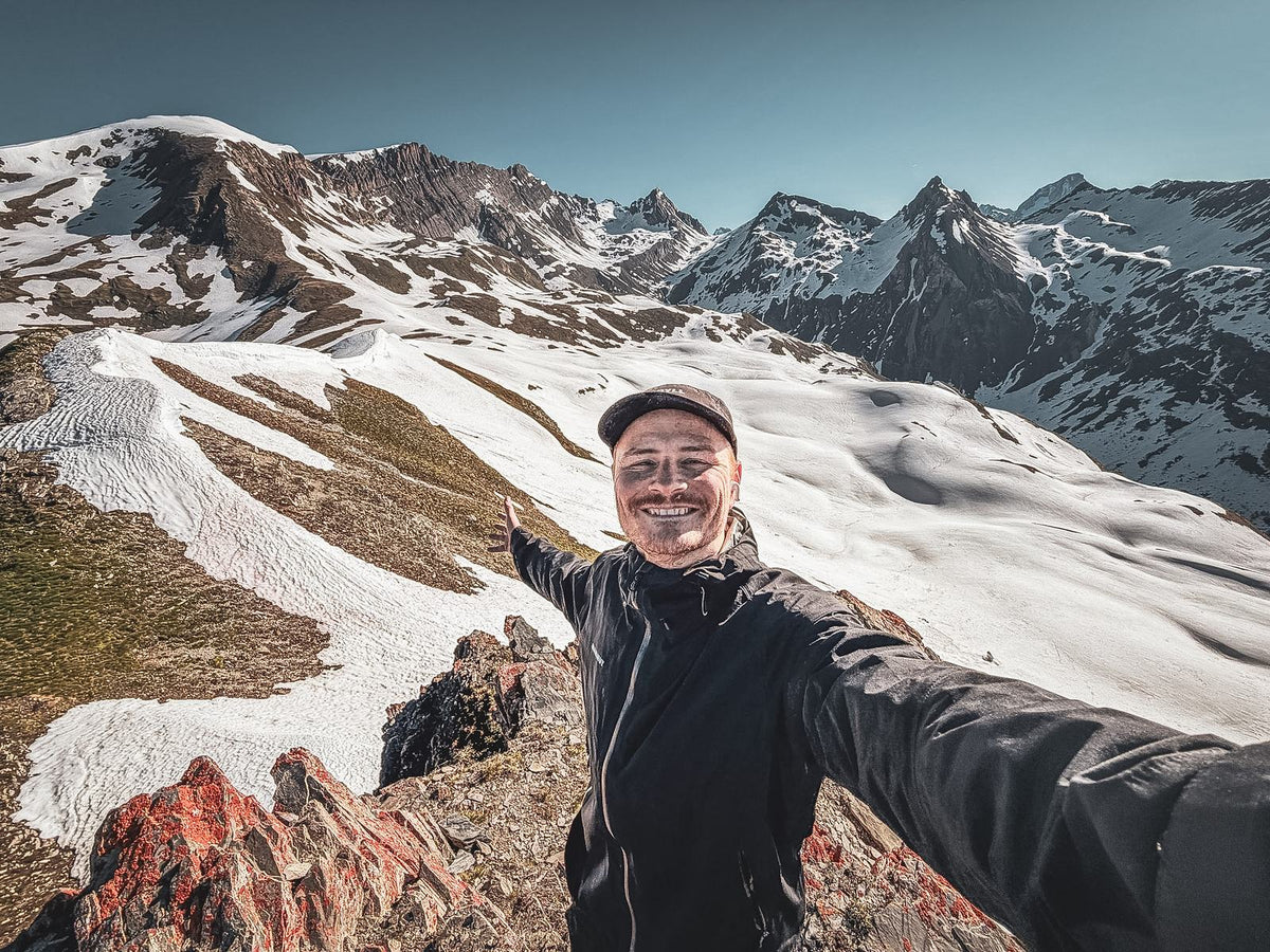 Pierre Biege auf einem Grat mit Schneefeldern, hinten verschneite Gipfel