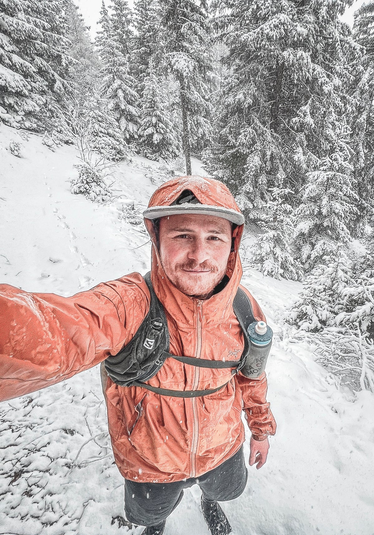 Pierre Biege im verschneiten Wald, orange Jacke und Laufweste